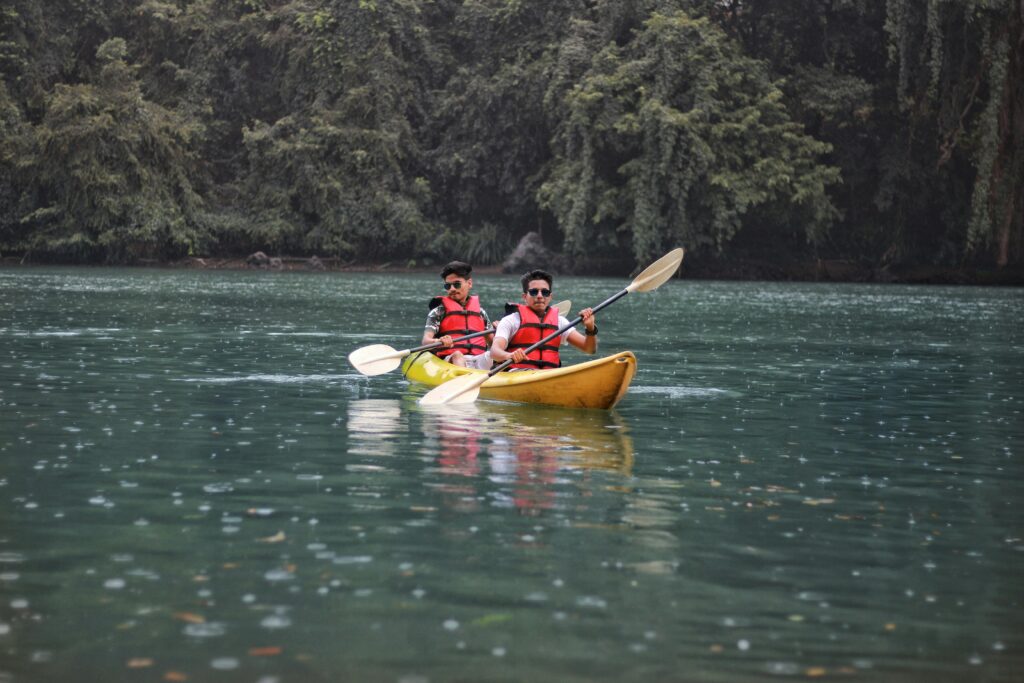 Two people enjoying kayaking on Kali River surrounded by lush greenery in Dandeli, India.